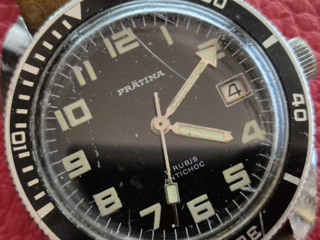 Nahaufnahme des Zifferblatts der Prätina Skin Diver mit großen Leuchtziffern, Datumsanzeige bei 3 Uhr und markanten Zeigern.
